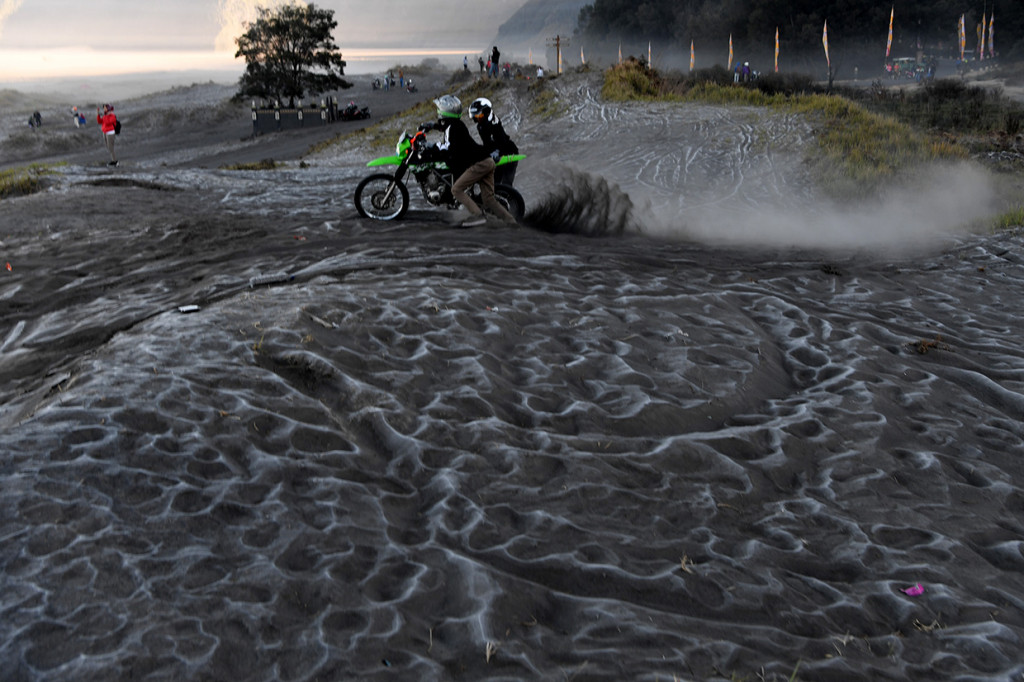 Pengunjung melintas di hamparan pasir yang diselimuti empun upas di kawasan Gunung Bromo, Probolinggo, Jawa Timur.