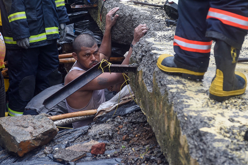 Seorang pria membantu personel pemadam kebakaran melakukan operasi penyelamatan terhadap korban runtuhnya tembok sebuah bangunan di Mumbai, Selasa, 2 Juli 2019.