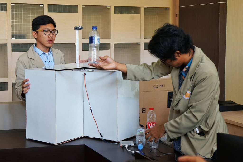 Mahasiswa Fakultas MIPA Universitas Gadjah Mada (UGM) Chairuman Nasution (kiri) dan Faiz Miftakhur Rozaqi menunjukkan mesin pemilah sampah otomatis karya mereka saat jumpa pers di Kampus UGM, Sleman, DI Yogyakarta, Selasa, 9 Juli 2019.