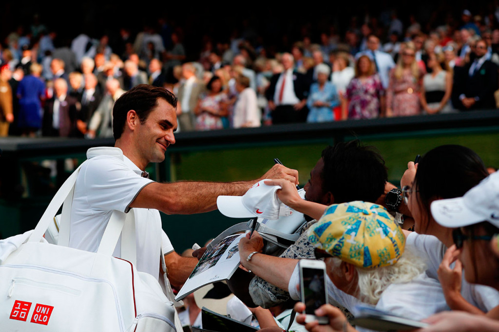 Petenis Swiss Roger Federer melayani permintaan foto dari para penggemarnya usai menuntaskan laga perempat final Wimbledon melawan petenis Jepang Kei Nishikori, Rabu, 10 Juli 2019 waktu setempat.