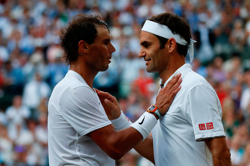 Petenis Swiss Roger Federer (kanan) mendapat ucapan selamat dari lawannya Rafael Nadal usai semifinal Wimbledon di All England Lawn Tennis Club, Wimbledon, Jumat, 12 Juli 2019 waktu setempat.