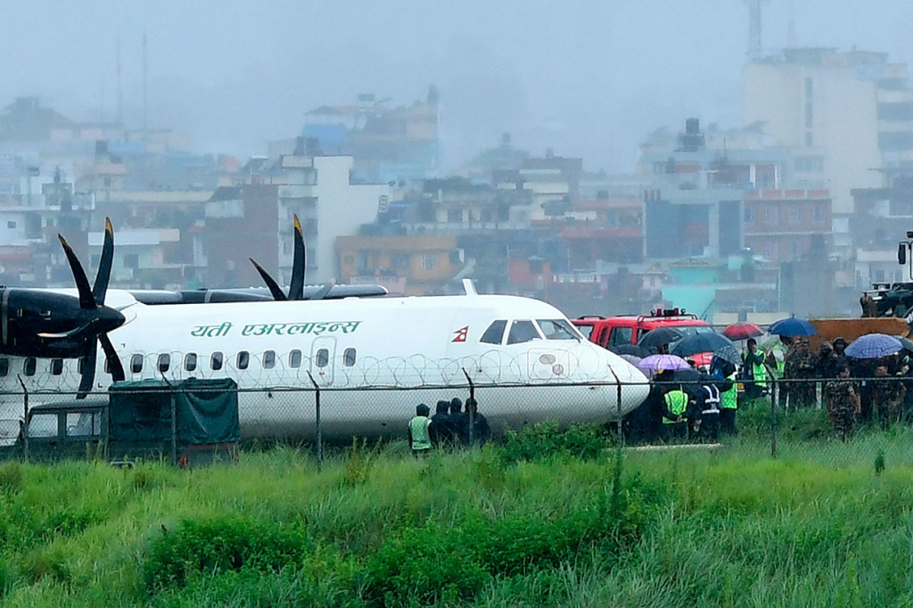 Tentara Nepal bersama tim penolong dan personel bandara berada di dekat pesawat Yeti Airlines yang tergelincir keluar landasan pacu di Bandara Intarnasional Tribhuvan, Kathmandu, Kamis, 12 Juli 2019.