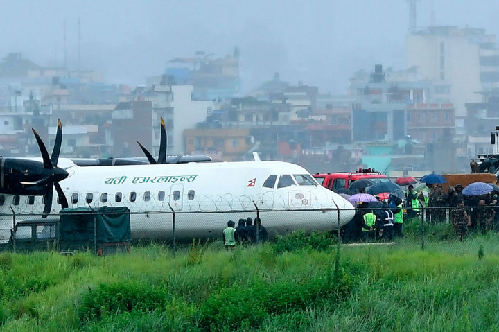 Tentara Nepal bersama tim penolong dan personel bandara berada di dekat pesawat Yeti Airlines yang tergelincir keluar landasan pacu di Bandara Intarnasional Tribhuvan, Kathmandu, Kamis, 12 Juli 2019.