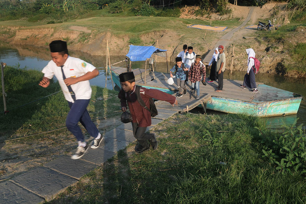 Sejumlah siswa menyeberangi sungai dengan perahu menuju sekolahnya Madrasah Tsanawiyah (MTs) Nasyrul Ulum di Desa Terkesi, Grobogan, Jawa Tengah. Antara Foto/Yusuf Nugroho