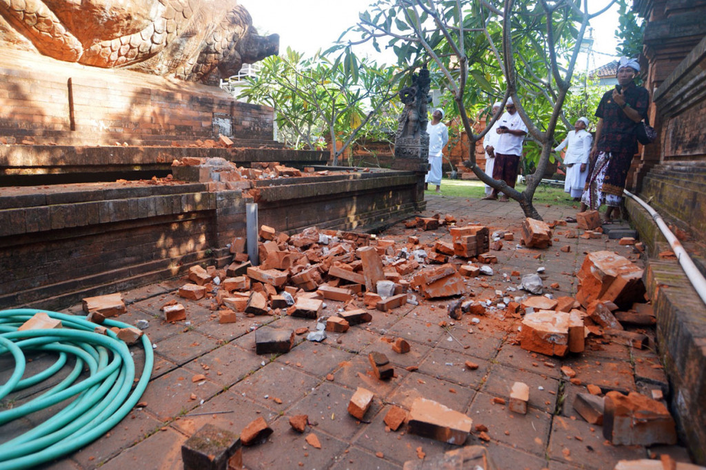 Pemuka agama Hindu memantau kerusakan pada bagian candi yang runtuh akibat gempa di Pura Lokanatha, Denpasar, Bali, Selasa, 16 Juli 2019. 