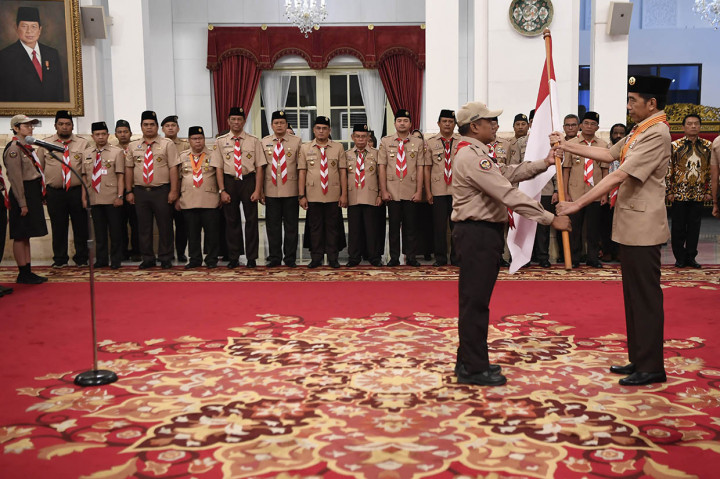 Presiden Joko Widodo (kanan) menyerahkan bendera Merah Putih saat upacara pelepasan Kontingen Gerakan Pramuka Indonesia menuju Jambore Pramuka Dunia XXIV di Istana Negara, Jakarta.