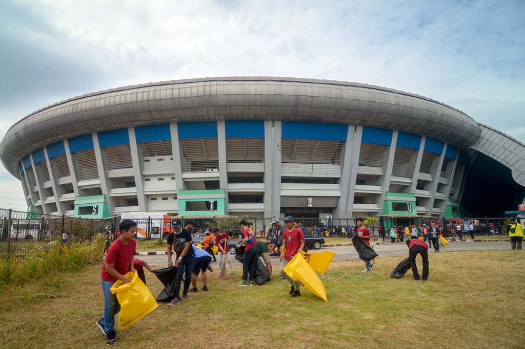 Relawan membersihkan rumput liar dan sampah yang sebelumnya berserakan di halaman Stadion Gelora Bandung Lautan Api (GBLA), Gedebage, Bandung, Jawa Barat, Sabtu, 20 Juli 2019. 