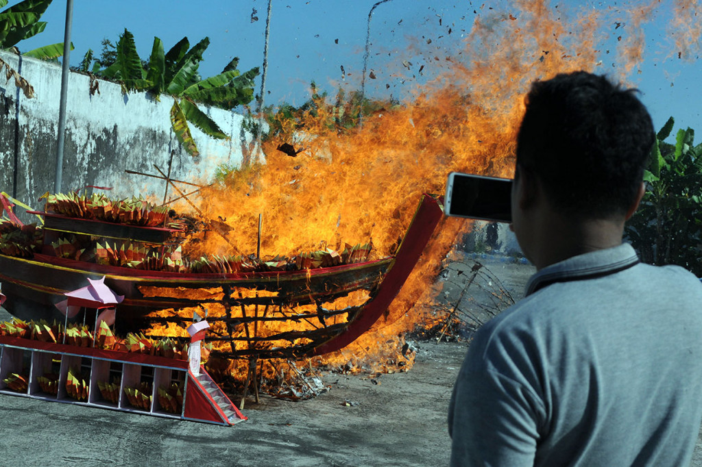 Warga mengabadikan pembakaran replika kapal saat memperingati Dewi Kwan Im mencapai kesempurnaan di Vihara Avalokitesvara, Pamekasan, Jawa Timur, Sabtu, 20 Juli 2019.