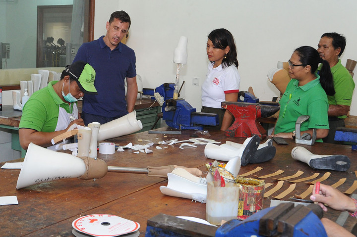 Mantan pesepak bola Manchester United Gary Neville (kedua kiri) mengamati aktivitas pembuatan kaki palsu oleh penyandang disabilitas saat mengunjungi Annika Linden Centre di Denpasar, Bali.
