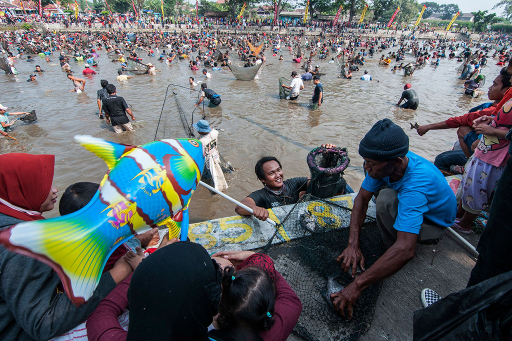 Warga menangkap ikan dengan jaring saat Tradisi Memet Ikan di Embung Gemblegan, Kalikotes, Klaten, Jawa Tengah, Sabtu, 27 Juli 2019. 