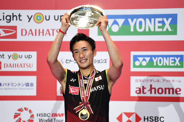 Pebulutangkis Jepang Kento Momota mengangkat trofi setelah menjadi juara Japan Open 2019.