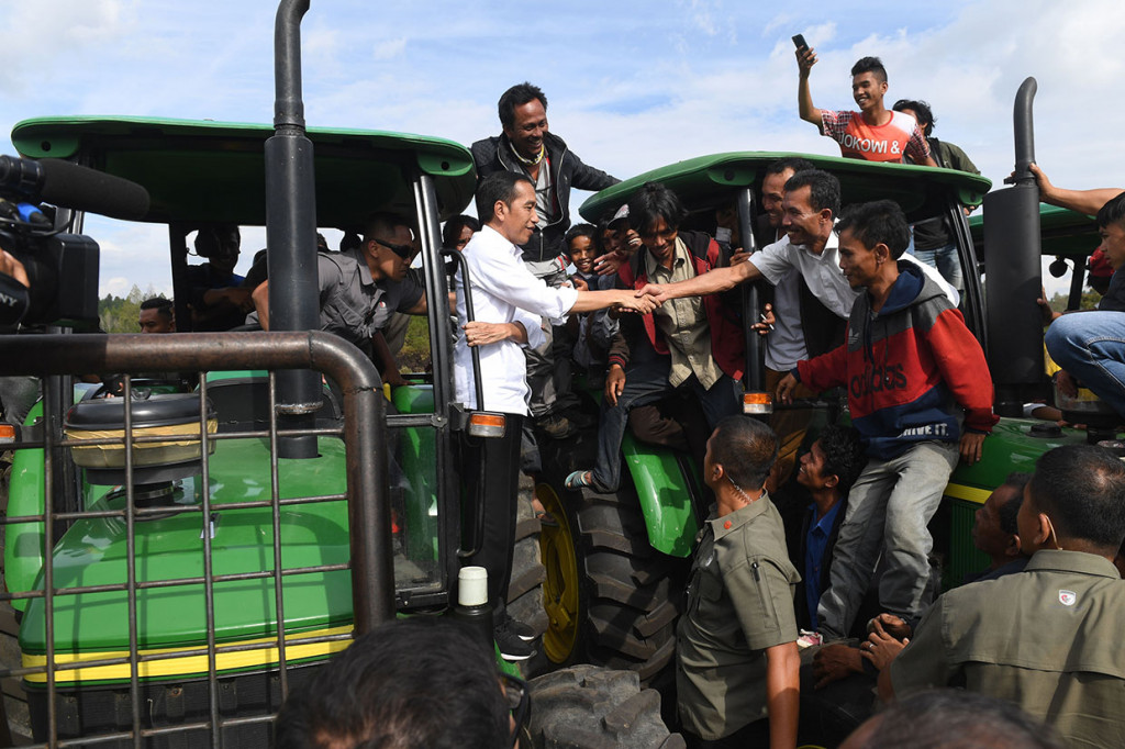 Presiden Joko Widodo (kiri) menyapa warga di atas traktor saat melakukan kunjungan kerja di Humbang Hasundutan.