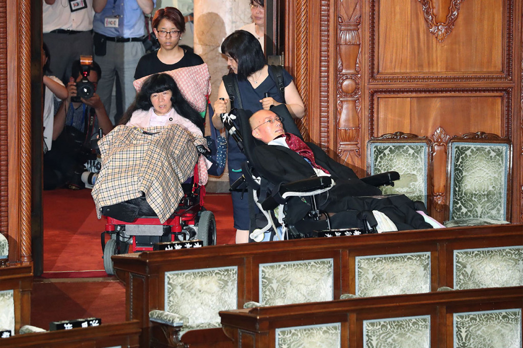 Dua anggota parlemen Jepang penyandang disabilitas kelumpuhan serius, Yasuhiko Funago (kanan) dan Eiko Kimura memasuki aula pleno Dewan Tinggi untuk menghadiri sesi luar biasa pemilihan pemimpin baru di Majelis Tinggi Jepang, Kamis, 1 Agustus 2019.