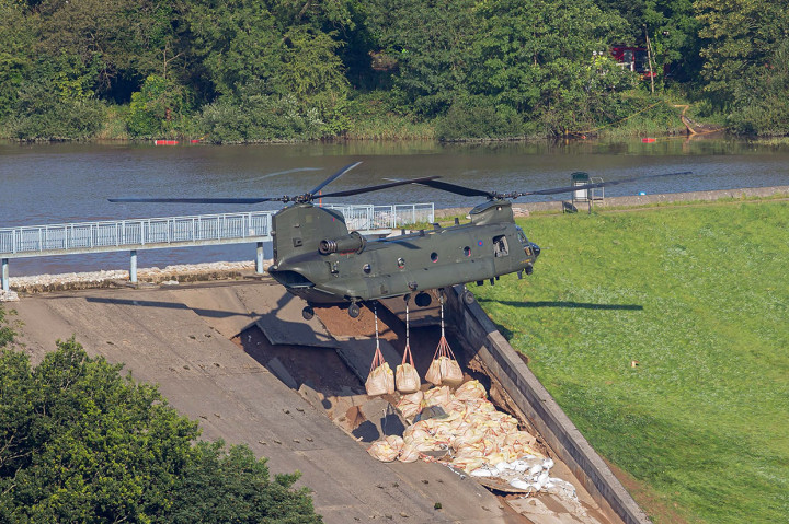 Personel menggunakan helikopter Chinook Royal Air Force (RAF) menurunkan kantong pasir untuk memperkuat spillway yang rusak dari bendungan Waduk Toddbrook di atas Kota Whaley Bridge di Inggris utara, Jumat, 2 Agustus 2019 waktu setempat.
