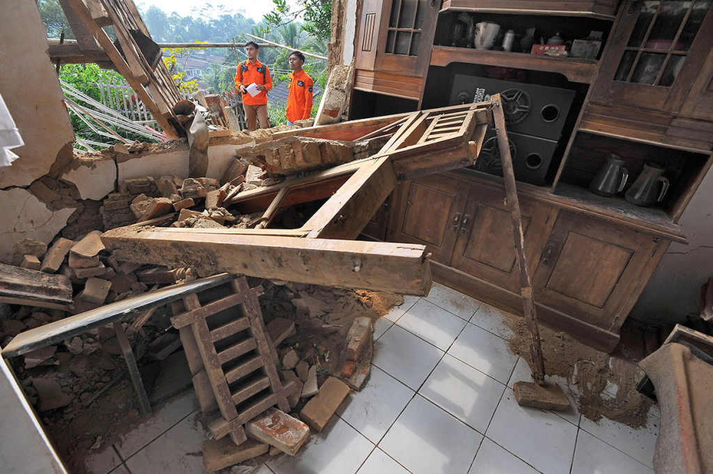 Relawan memeriksa rumah warga yang rusak akibat diguncang gempa di Kampung Karoya, Mandalawangi, Pandeglang, Banten.