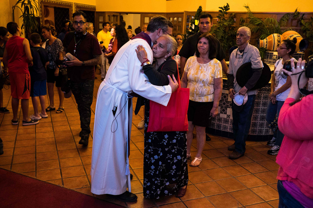 Pastor Michael Lewis memeluk keluarga korban penembakan massal di El Paso, setelah upacara di Gereja Saint Pius X.