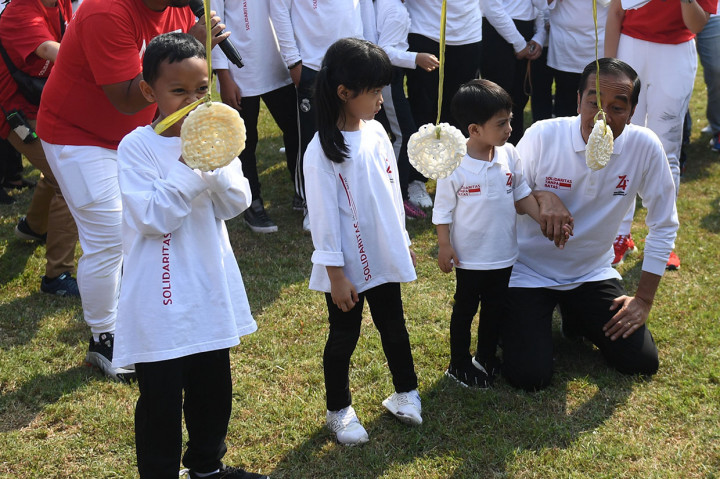 Presiden Joko Widodo (kanan) mengajak cucunya Jan Ethes (kedua kanan) mengikuti lomba makan kerupuk saat 