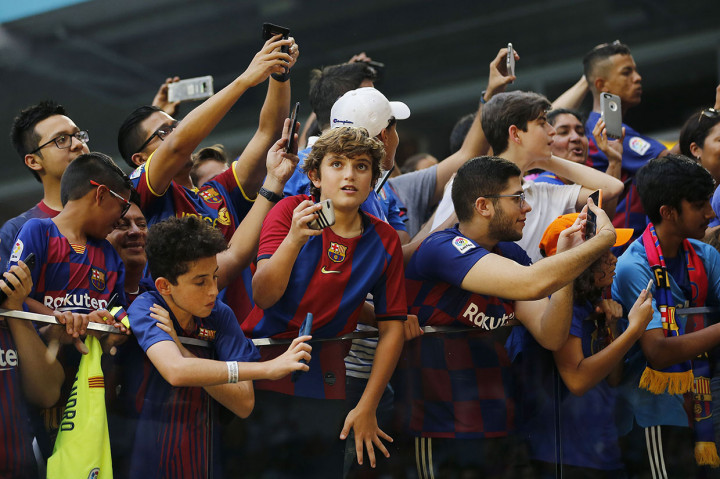 Para penggemar Barcelona mengabadikan jalannya laga dengan ponsel mereka.