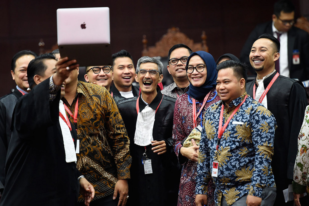 Komisioner Komisi Pemilihan Umum (KPU) Evi Novida Ginting (ketiga kanan) bersama sejumlah anggota tim kuasa hukum KPU dan perwakilan Bawaslu berswa foto usai sesi pertama sidang putusan akhir untuk perkara sengketa hasil Pemilu Legislatif 2019 di Ruang Sidang Pleno Gedung Mahkamah Konstitusi (MK), Jakarta.