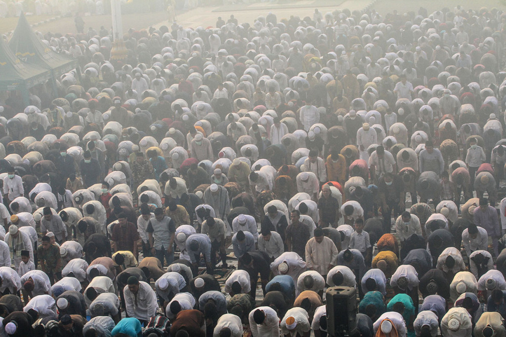 Ribuan umat muslim mendengarkan ceramah saat akan melaksanakan Sholat Idul Adha di halaman Masjid Raya Annur dengan kondisi kabut asap karhutla yang menyelimuti Kota Pekanbaru, Riau.