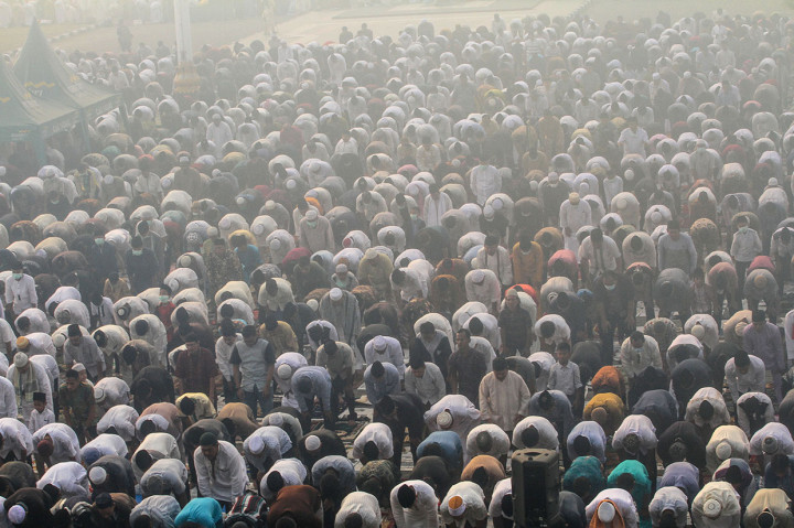 Ribuan umat muslim mendengarkan ceramah saat akan melaksanakan Sholat Idul Adha di halaman Masjid Raya Annur dengan kondisi kabut asap karhutla yang menyelimuti Kota Pekanbaru, Riau.