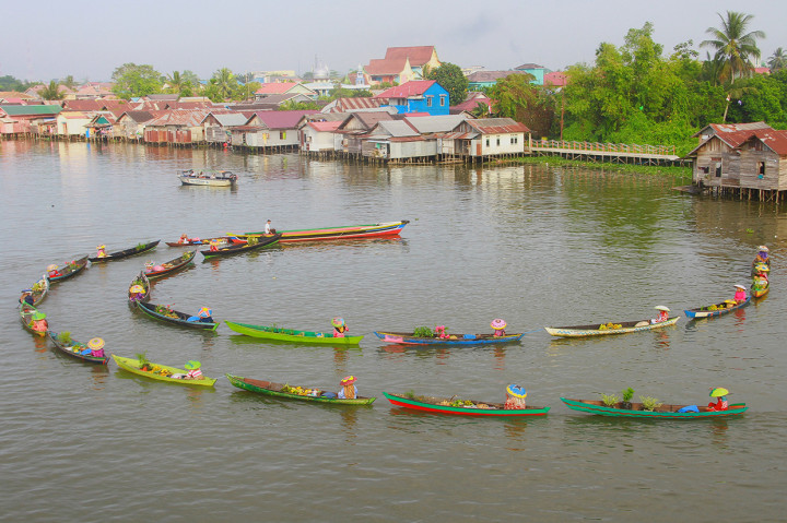 Pedagang pasar terapung melakukan atraksi jukung meliuk-liuk di sungai Martapura, Banjarmasin, Kalimantan Selatan.
