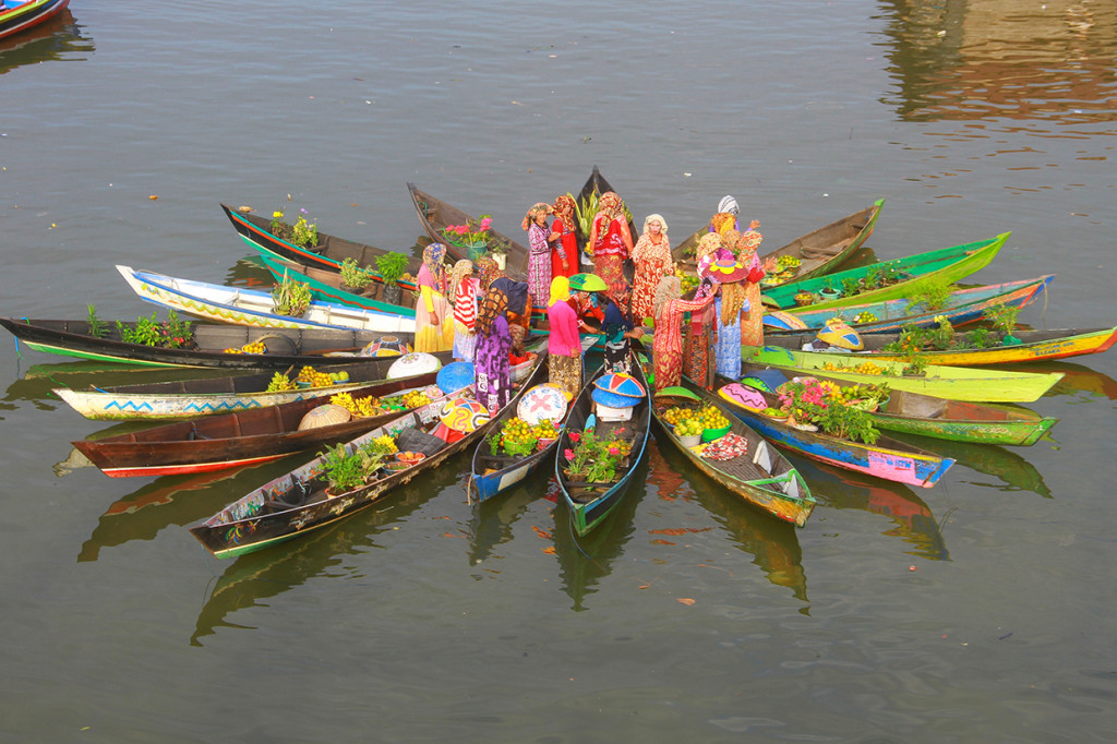 Pedagang pasar terapung melakukan atraksi jukung membentuk bunga mekar di sungai Martapura, Banjarmasin, Kalimantan Selatan.