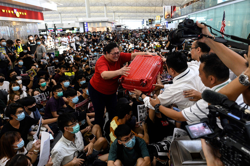 Penumpang berusaha masuk pintu keberangkatan Bandara Hong Kong.
