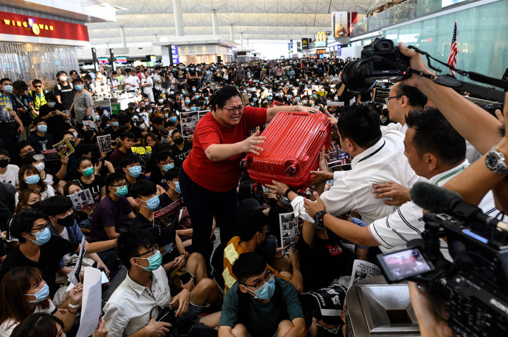 Penumpang berusaha masuk pintu keberangkatan Bandara Hong Kong.