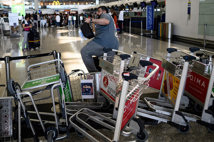 Para demonstran memindahkan troli untuk mencegah penumpang menggunakan lift dan eskalator menuju pintu keberangkatan di lantai bawah terminal 2. 