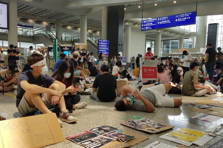 Demonstran masih ada yang melakukan aksi dengan duduk di lobi utama, meskipun jumlahnya tidak sebesar dua hari sebelumnya yang mengakibatkan salah satu bandara tersibuk di dunia itu mengalami kelumpuhan.  
