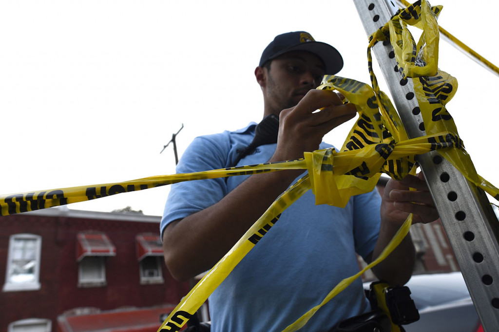 Petugas memasang garis polisi di dekat sebuah rumah tempat berlangsungnya baku tembak dengan seorang pria dalam penggerebekan narkoba di Philadelphia, Pennsylvania, Rabu, 14 Agustus 2019 waktu setempat.