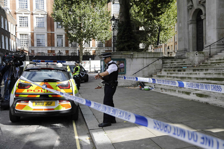 Garis polisi telah dipasang di sekitar pintu masuk Kementerian Dalam Negeri Inggris, sementara petugas keamanan dan petugas polisi berdiri di luar. Dua mobil polisi ditempatkan di luar dengan beberapa lainnya diparkir di dekatnya.