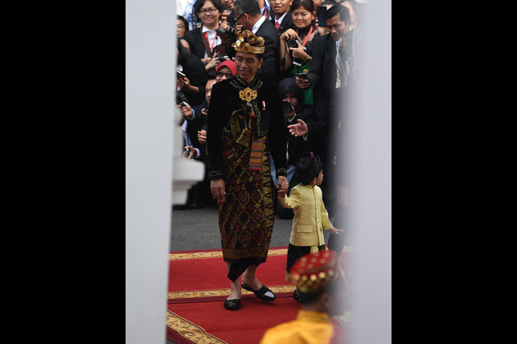 Presiden Joko Widodo ditemani cucunya Jan Ethers tiba di Istana Merdeka, Jakarta, Sabtu, 17 Agustus 2019. Jokowi mengenakan pakaian adat dari Klungkung, Bali, berwarna hitam dengan brokat emas lengkap dengan kain dan hiasan kepala juga dengan motif emas. Sementara Jan Ehtes juga berpakaian adat Bali dengan berbagai warna dan corak. 