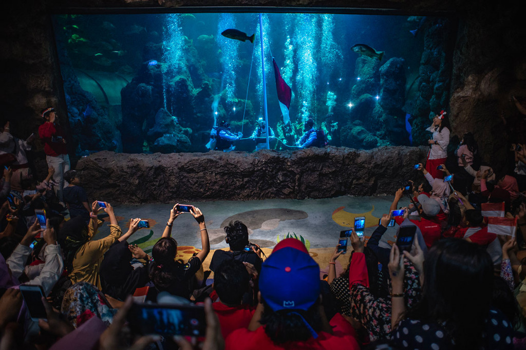 Pengunjung antusias menyaksikan penyelam melaksanakan upacara bendera peringatan HUT ke-74 RI di dalam akuarium utama Seaworld Ancol, Jakarta.