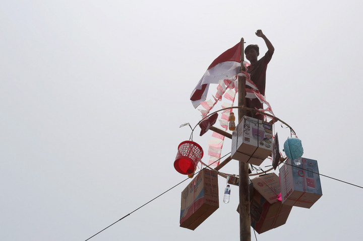 Seorang anak berhasil mencapai puncak saat perlombaan panjat pinang dalam rangka memeriahkan HUT ke-74 Kemerdekaan RI di sekitar lokasi terdampak bocornya minyak dari anjungan YYA milik Pertamina di lapangan desa Cemara Jaya, Karawang.