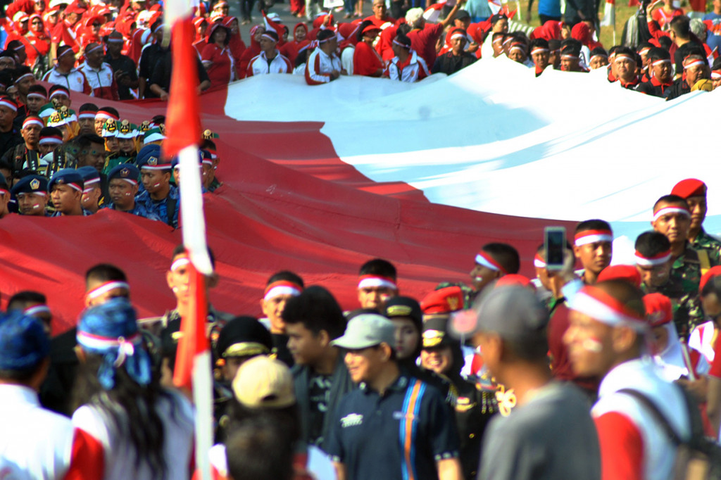Sejumlah anggota TNI, Kepolisian, organisasi dan komunitas mengarak bendera merah putih di jalan Sudirman, Kota Bogor, Jawa Barat.
