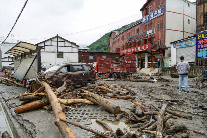 Kayu gelondongan berserakan sementara beberapa mobil rusak parah akibat tanah longsor yang disebabkan hujan deras disertai banjir bandang di daerah Wichuan, Provinsi Sichuan, Tiongkok barat daya, Kamis, 22 Agustus 2019.