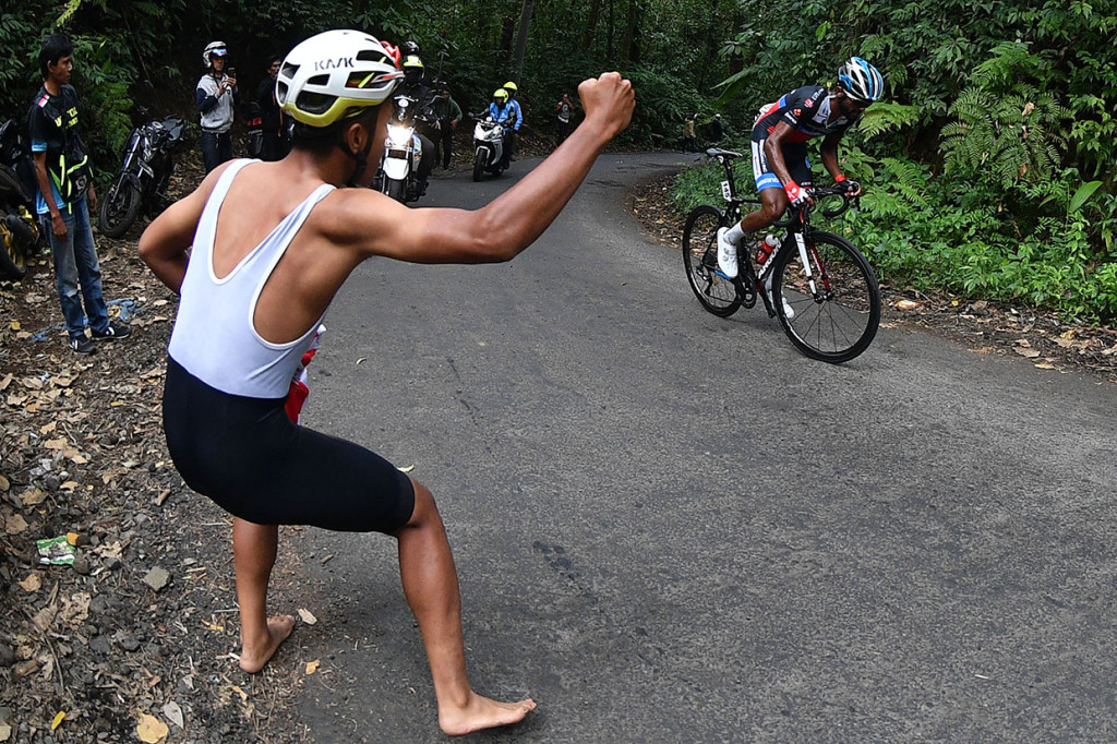 Seorang pria memberi semangat pebalap sepeda Metkel Eyob menaiki tanjakan pada etape keempat Tour de Indonesia 2019 didataran tinggi Ijen, Banyuwangi, Jawa Timur.
