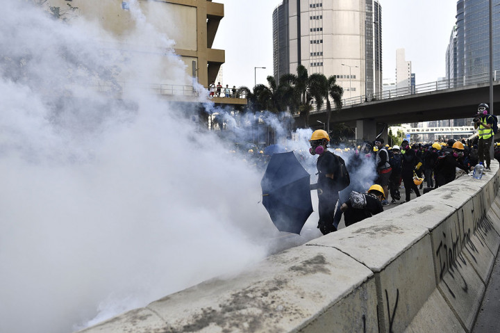 Polisi anti huru-hara Hong Kong berusaha membubarkan para demonstran dengan menembakkan gas air mata. 
