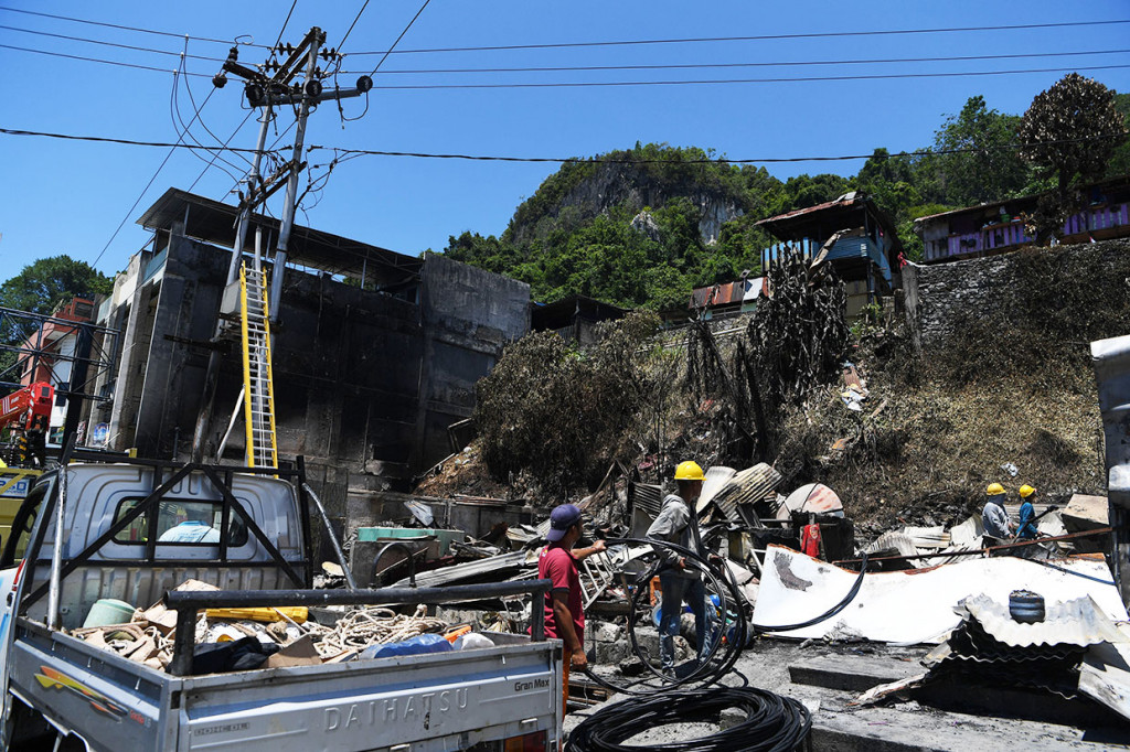 Petugas menata sambungan listrik yang rusak di salah satu rumah warga yang terbakar pascaunjuk rasa yang diwarnai aksi anarkis di Jayapura.