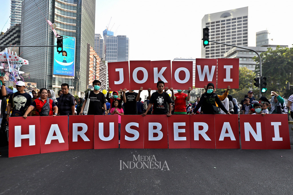 Sejumlah warga yang mengatasnamakan Koalisi Masyarakat Sipil Antikorupsi membentangkan tulisan 'Jokowi Harus Berani'. 
