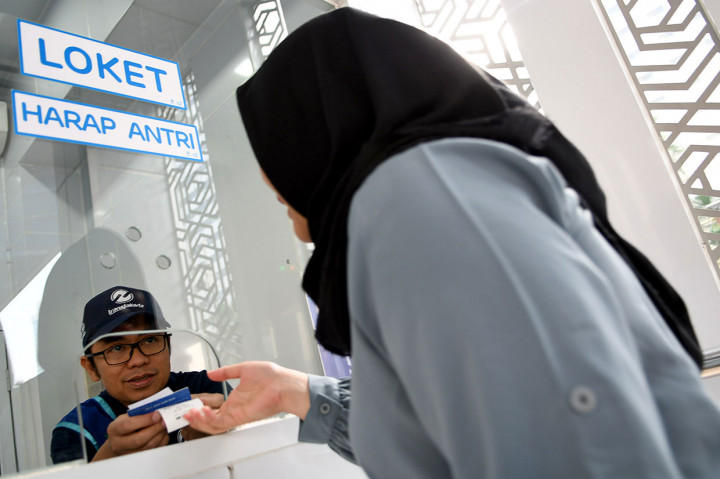 Direktur Keuangan TransJakarta Welfizon Yuza melayani calon penumpang mengisi ulang uang elektronik di Halte TransJakarta Bundaran Hotel Indonesia, Jakarta.