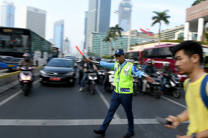 Dirut TransJakarta Agung Wicaksono menghentikan kendaraan bermotor ketika pejalan kaki melintasi 'pelican cross' di Halte TransJakarta Bundaran Hotel Indonesia, Jakarta. 