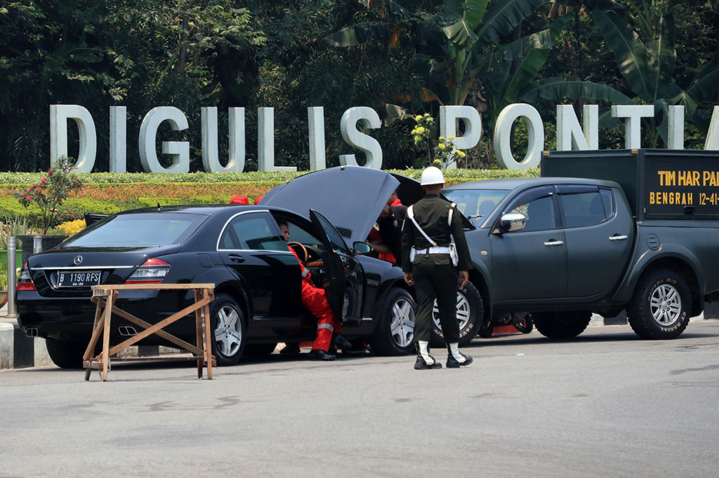 Prajurit TNI AD mengawal teknisi yang memperbaiki mesin mobil Kepresidenan Indonesia-1 yang sudah berganti plat di lokasi acara Presiden Joko Widodo membagikan sertifikat Tanah Objek Reforma Agraria (TORA) di Taman Digulis, Pontianak, Kalimantan Barat, Kamis, 5 September 2019. 