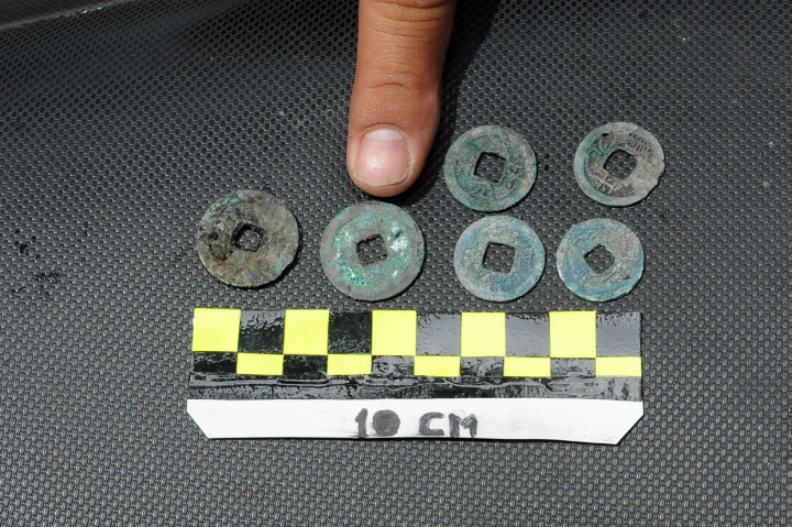 Ratusan koin tersebut ditemukan berkelompok-kelompok dan terikat tali ijuk. Di koin yang tengahnya berlubang tersebut ditemukan tulisan yang identik dengan huruf Mandarin.