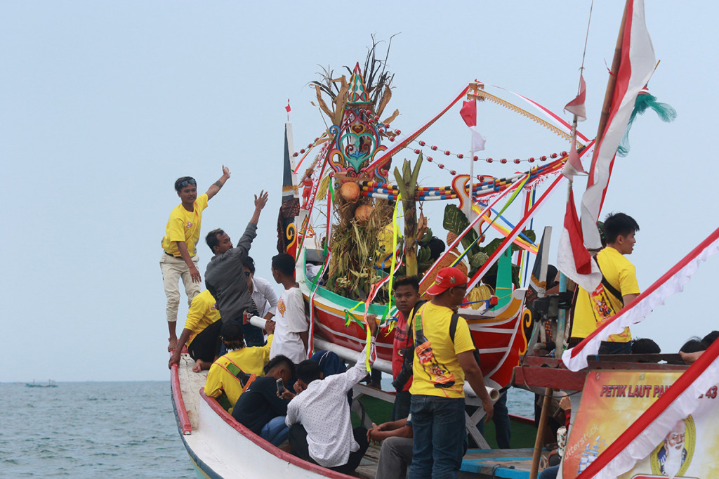 Warga membawa gitik (sesaji) yang akan dilarung ke laut pada tradisi petik laut pancer di Banyuwangi, Jawa Timur.