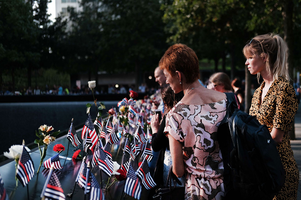 Warga berkumpul sambil memanjatkan doa di National September 11 Memorial, New York City untuk memperingati 18 tahun serangan teroris 9/11 yang menewaskan hampir 3 ribu orang.