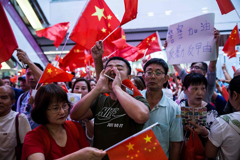 Ratusan demonstran pro-Beijing mengibarkan bendera China dan meneriakkan slogan.
