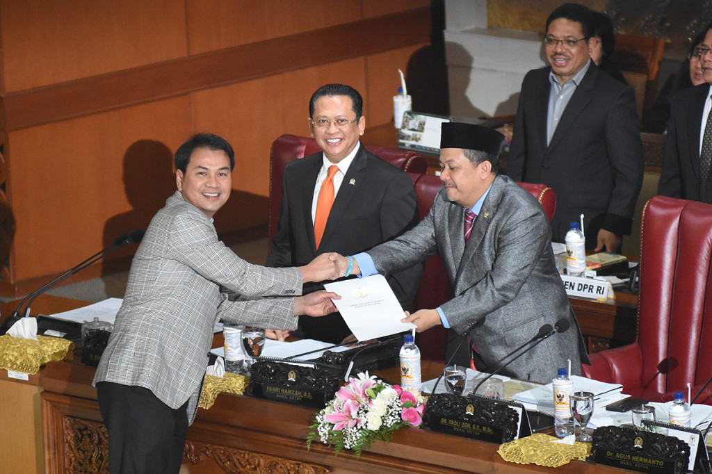 Ketua Komisi III DPR Aziz Syamsuddin (kiri) menyerahkan laporan hasil uji kelayakan dan kepatutan Capim KPK kepada Wakil Ketua DPR selaku Pimpinan Sidang Fahri Hamzah (kanan) didampingi Ketua DPR Bambang Soesatyo (tengah) pada Rapat Paripurna Pengesahan Pimpinan KPK terpilih periode 2019-2023 di Kompleks Parlemen, Senayan, Jakarta.